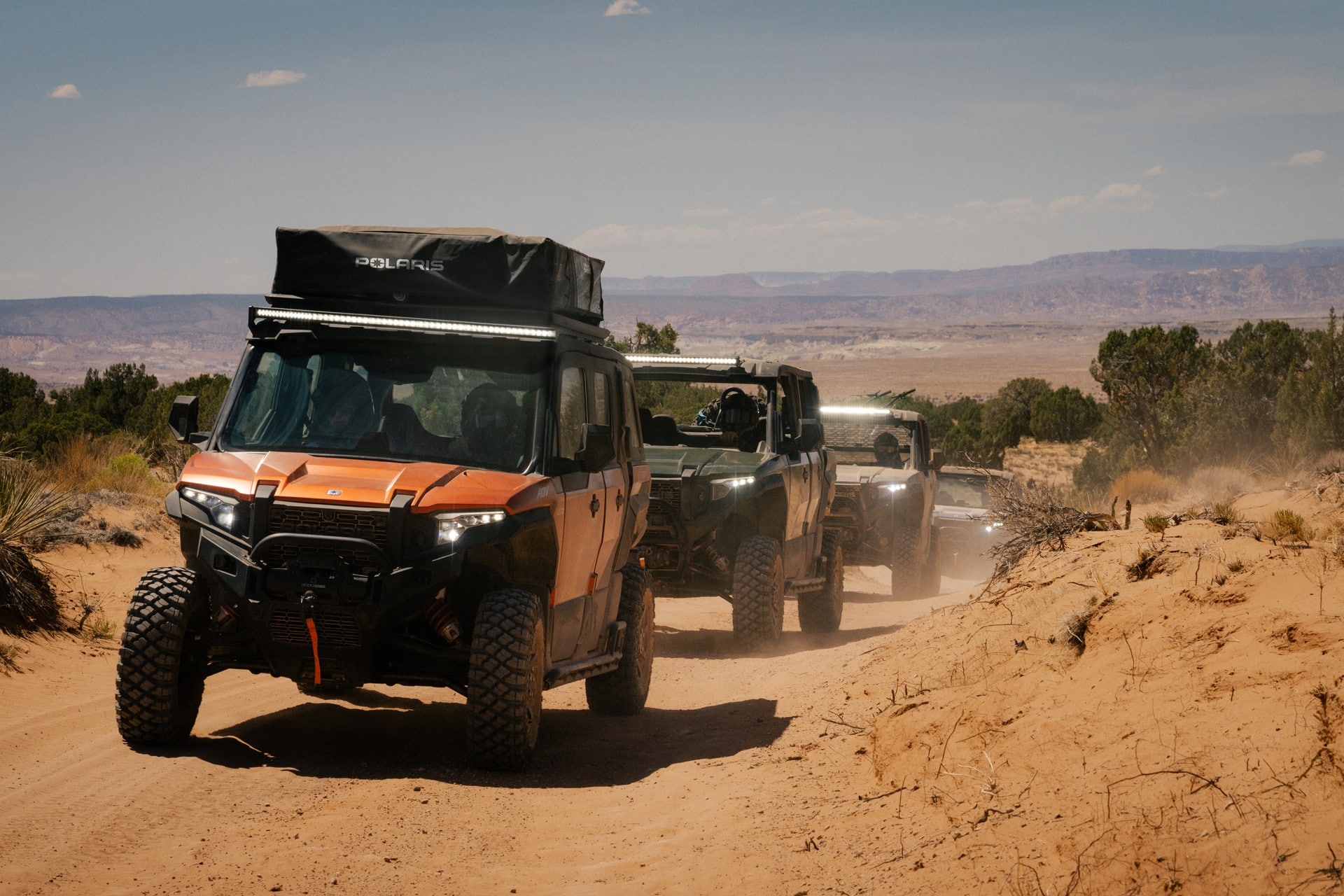 A lineup of Polaris XPEDITION driving through the dusty trails.